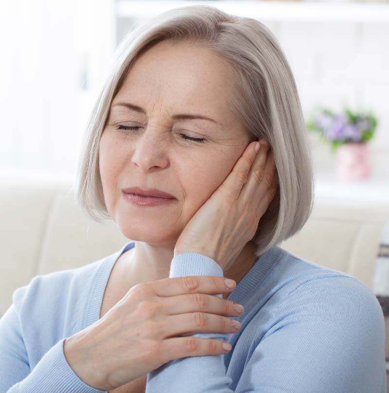 Woman holding her ear trying to stop the ringing in her ear she is experiencing. 