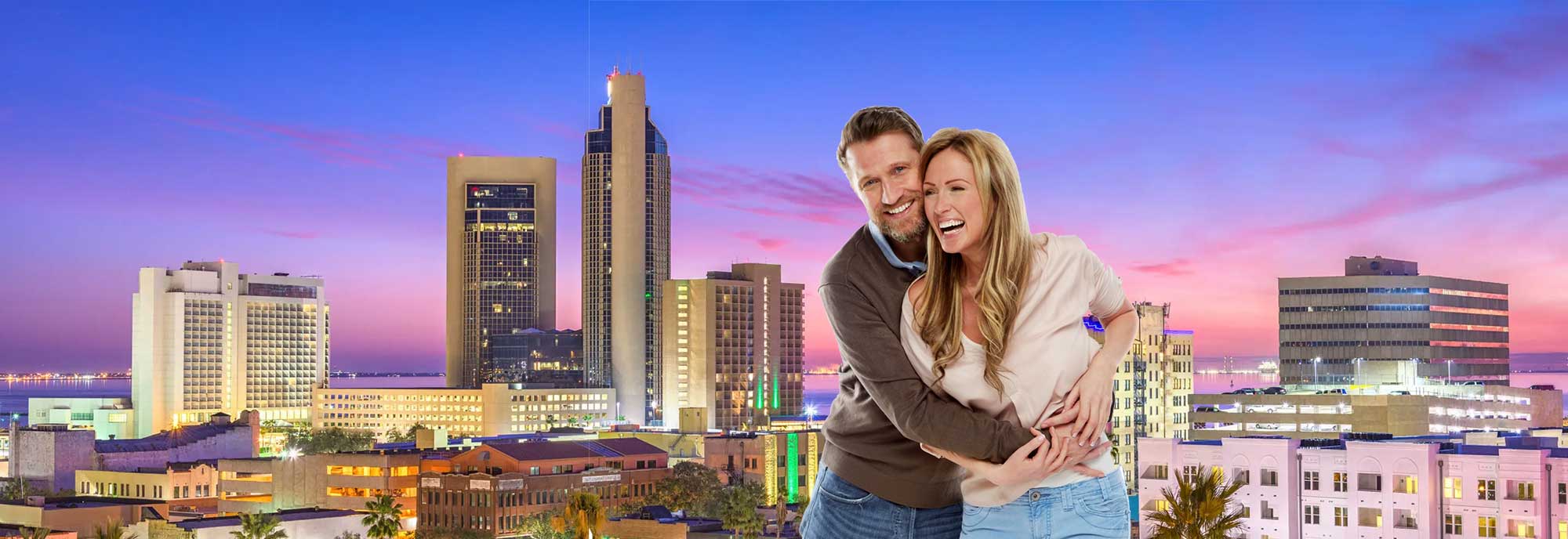 Couple laughing in front of the Corpus Christie skyline. 